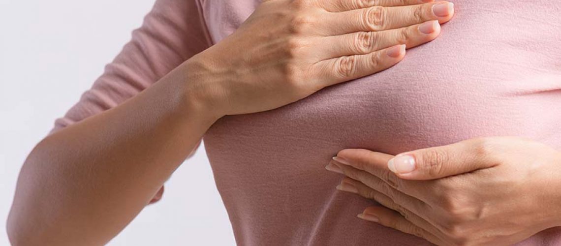 Ženska osoba u majci se drži za dojku - bol u dojkama
